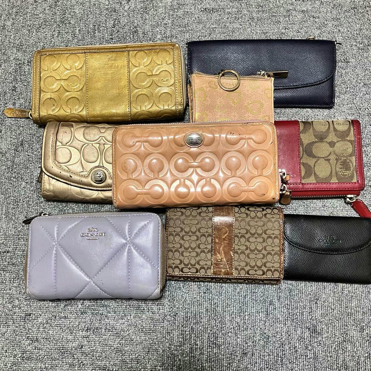Multiple COACH wallets and small leather accessories arranged on a carpeted floor.