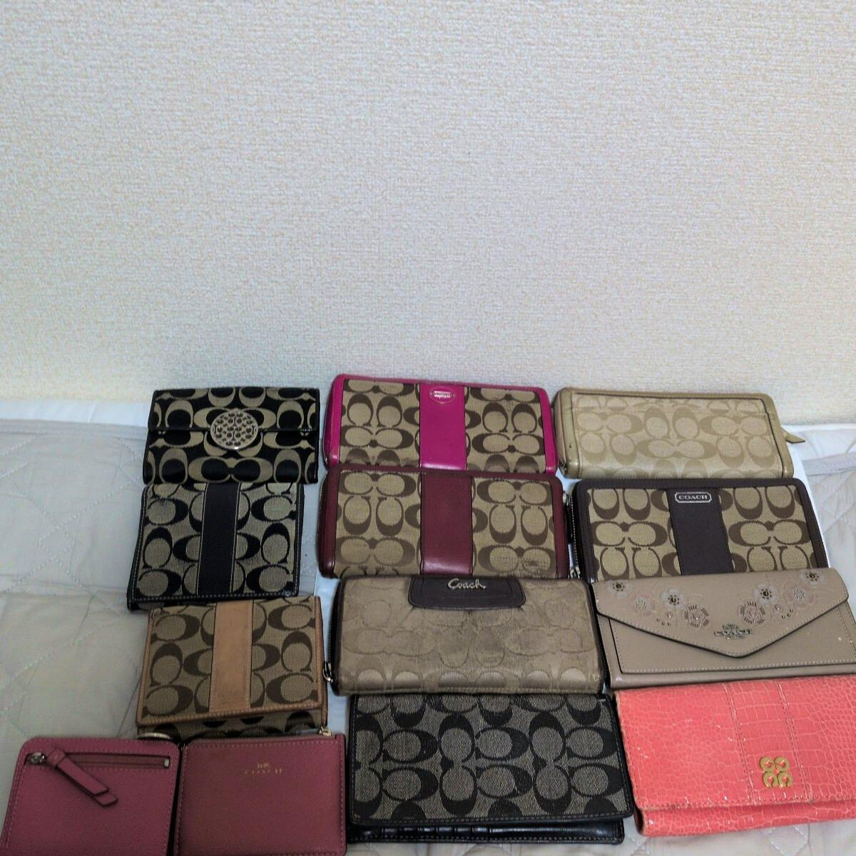 Multiple COACH wallets and small wallets arranged on a flat surface showing signature canvas patterns and colors.