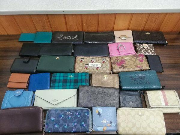 A collection of used COACH wallets and coin purses arranged on a wooden surface.