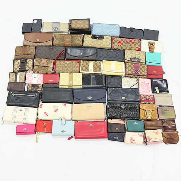 A laid-out assortment of Coach wallets and small leather goods on a white background.