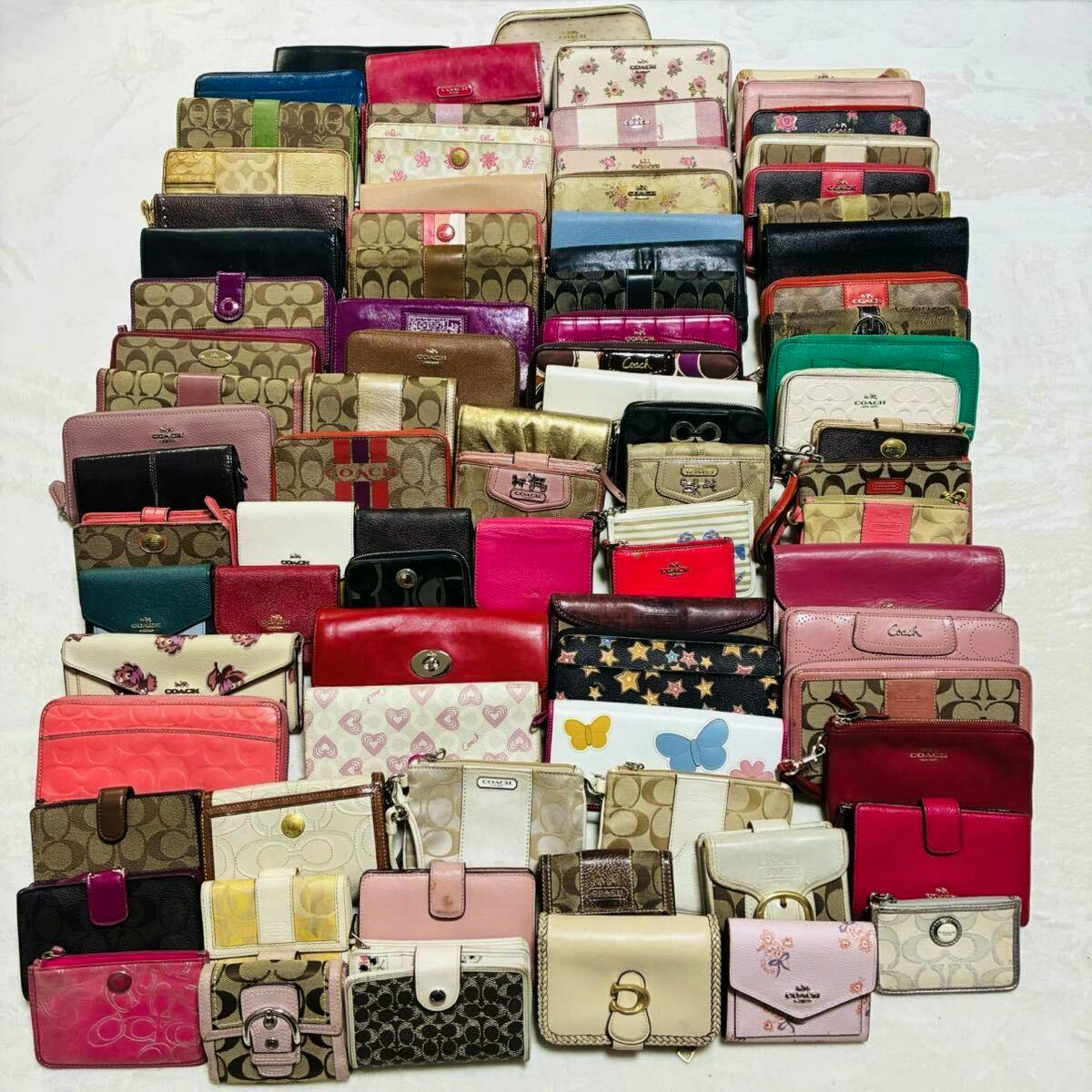A large assortment of Coach wallets, coin cases, and pouches arranged on a white surface.