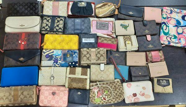 Spread of Coach wallets, pouches, and small leather goods arranged on a table with a small label reading '0901G112'.