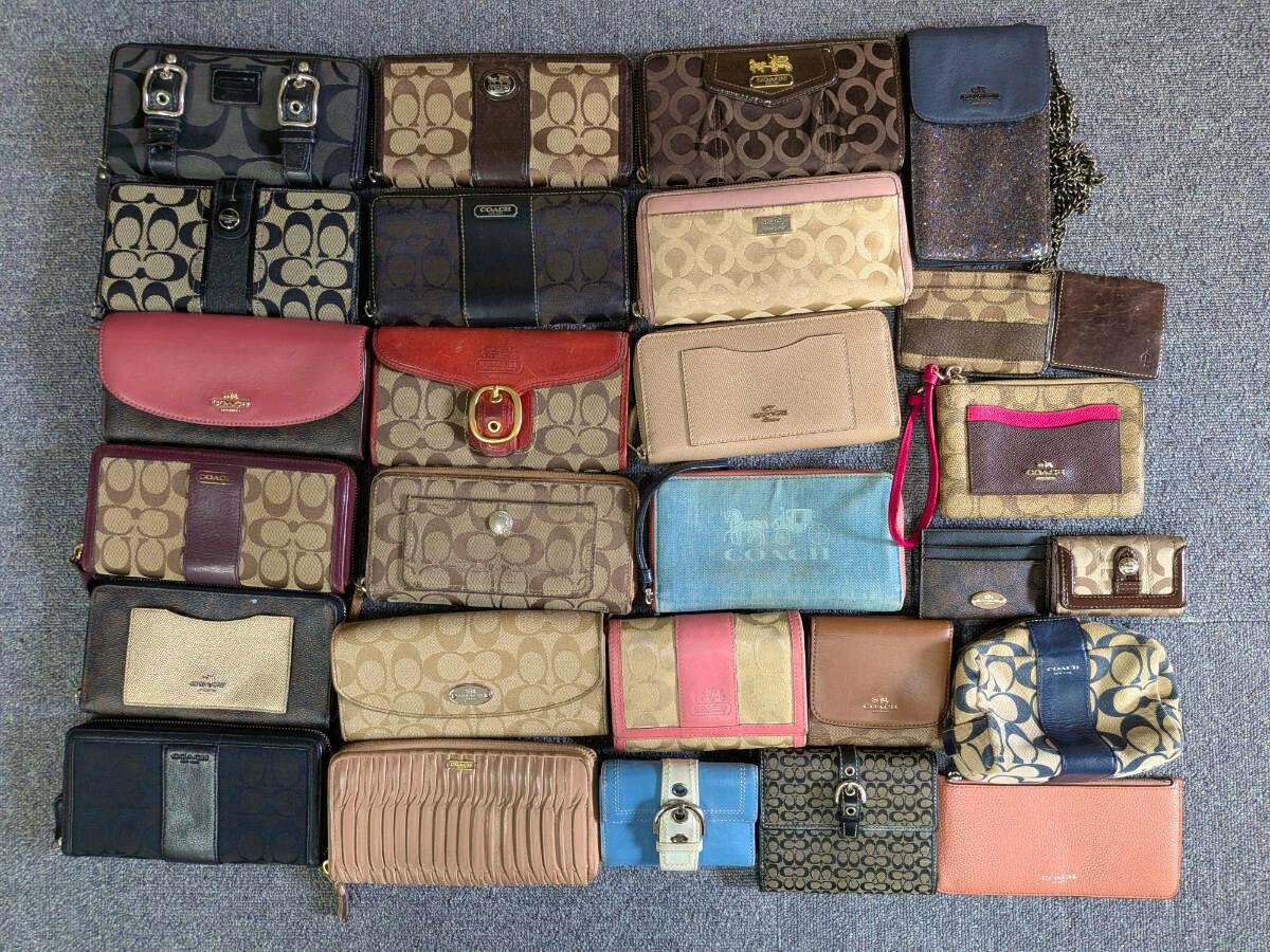 A flat-lay photo showing a bulk set of assorted COACH wallets and small canvas leather goods arranged on a gray carpet.