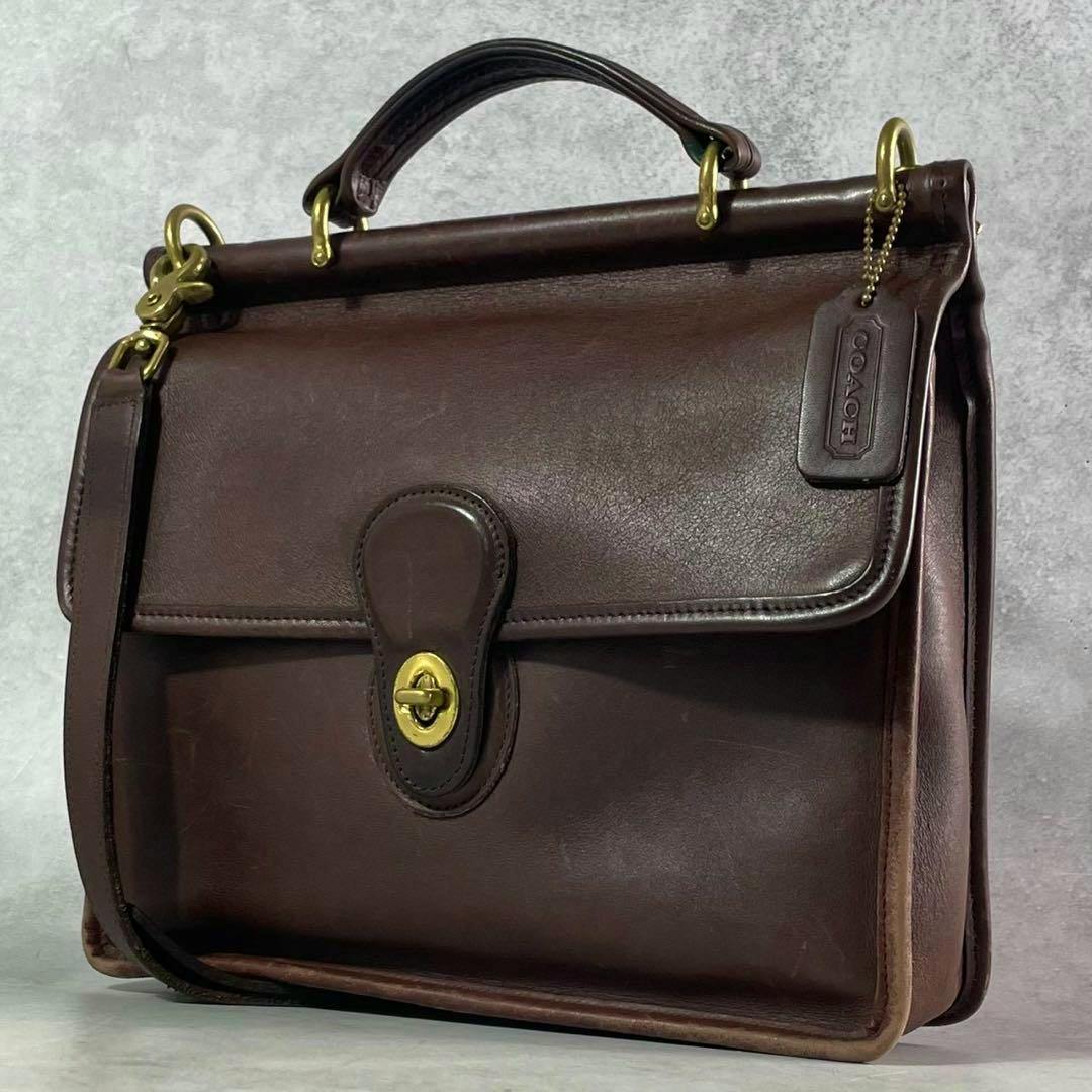 Brown COACH Willis leather shoulder bag with turnlock closure and top handle shown in a three-quarter view.