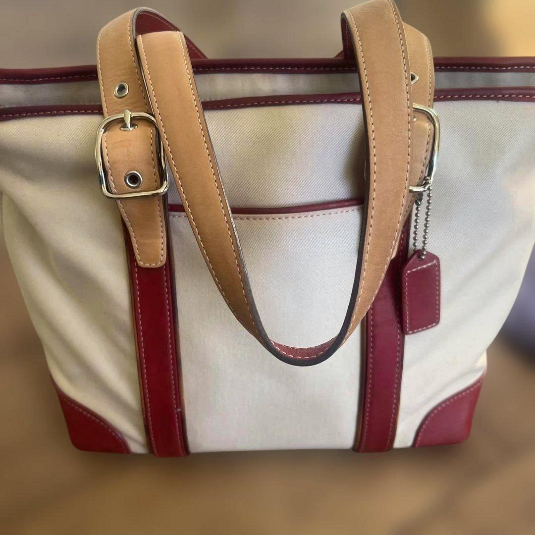 Beige canvas COACH ladies' handbag with red leather trim, tan straps, and a hanging leather tag.