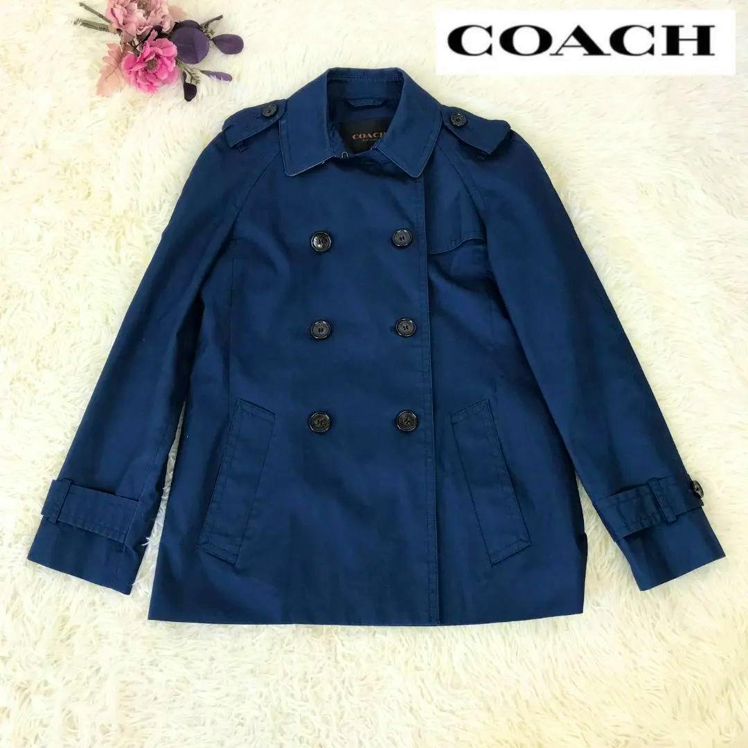 Navy blue women’s COACH cotton half-length trench coat laid flat showing double-breasted front and pockets.
