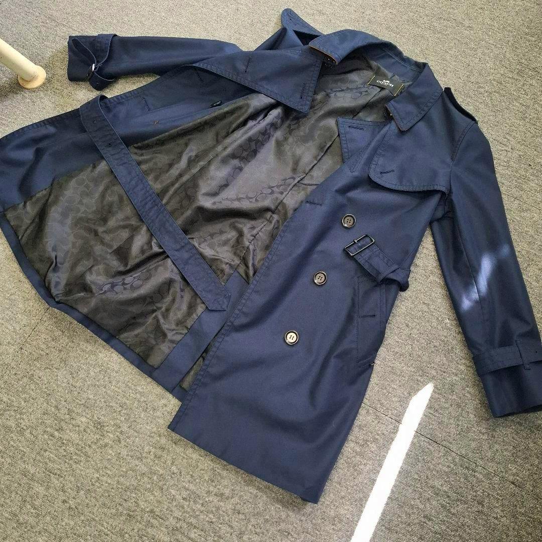 Navy COACH short women's trench coat laid flat and opened, showing the inner lining, buttons, and belt.
