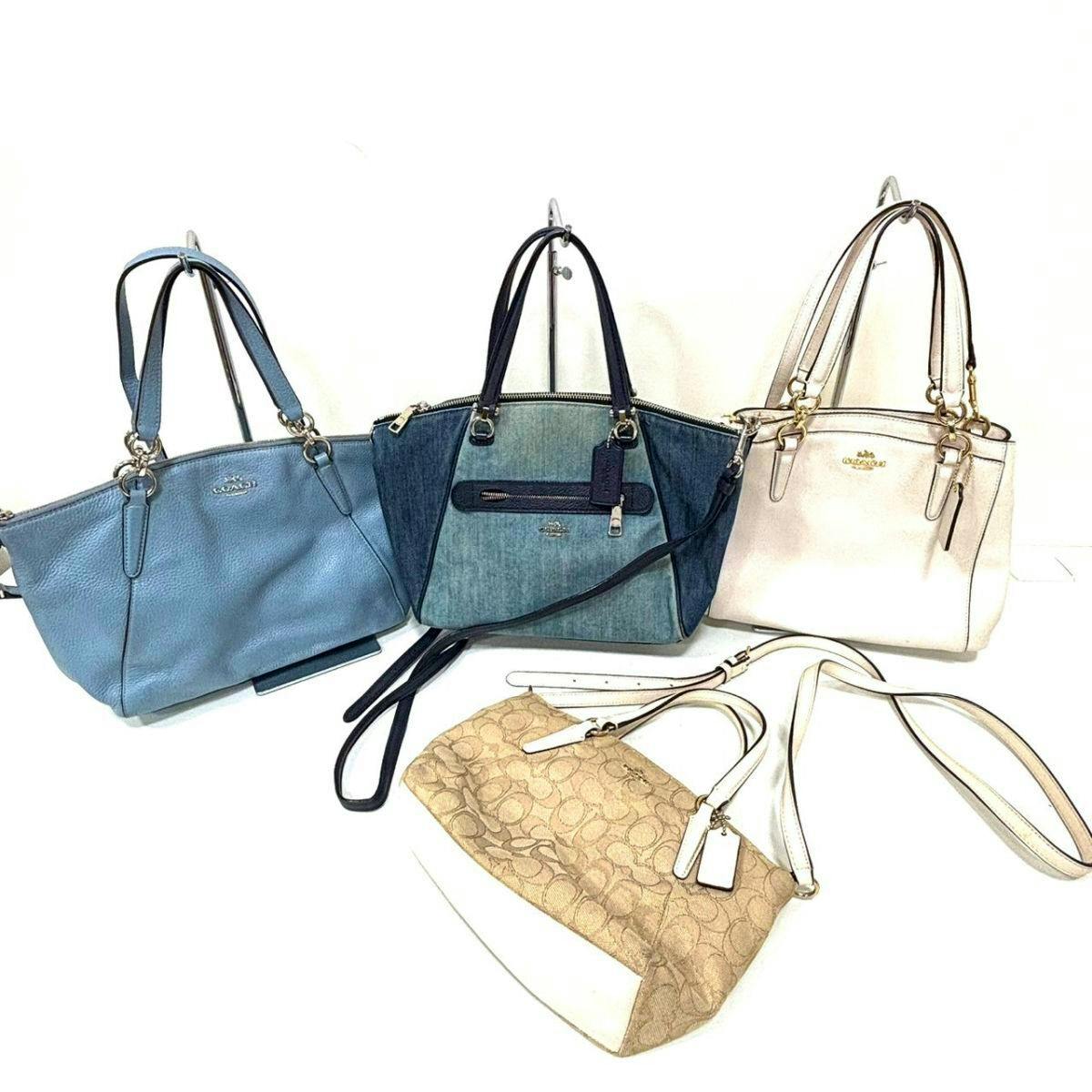 Four COACH handbags and shoulder bags arranged on a white background, including a light blue leather bag, a denim two-tone bag, a cream leather bag, and a beige signature canvas bag.