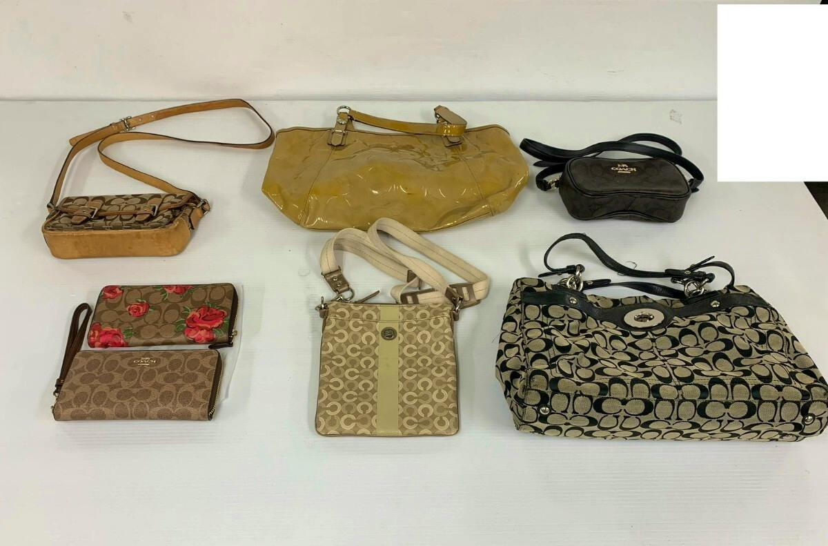 Seven Coach bags and wallets arranged on a white surface, showing multiple signature-print handbags, a yellow patent handbag, and several small wallets.
