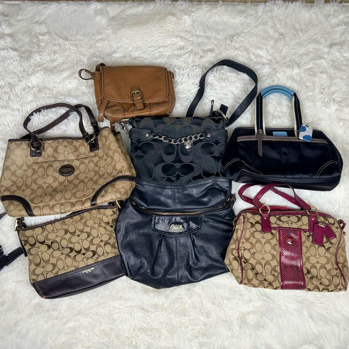 Seven Coach handbags and pouches arranged on a white rug, showing different styles and colors.