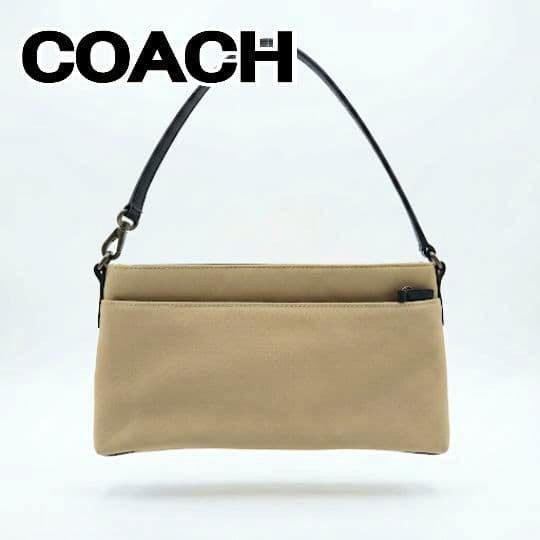Beige COACH one-shoulder handbag with a black strap shown against a white background.