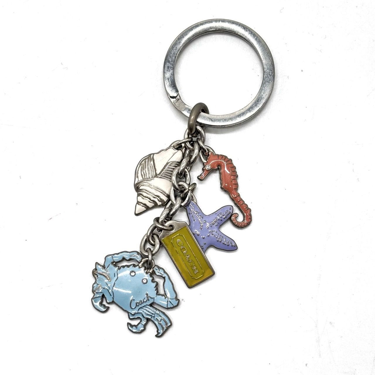 Metal Coach keychain with marine animal charms: crab, starfish, seahorse, shell, and a small Coach tag.