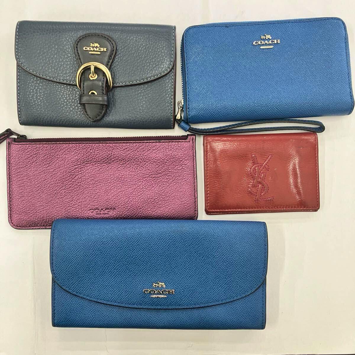 Several wallets and a small card case laid flat, showing multiple Coach wallets and a red Yves Saint Laurent card case.