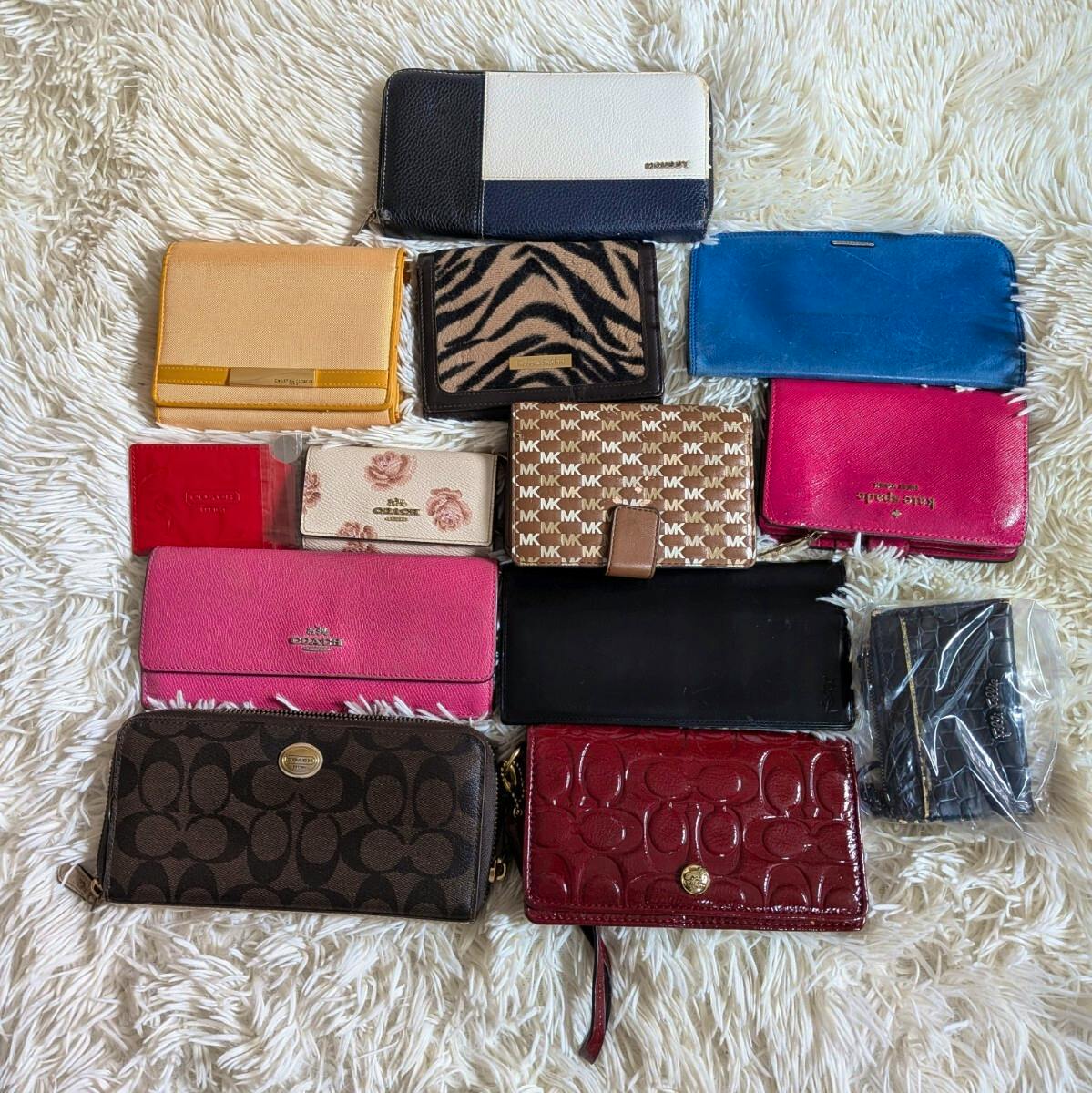 A selection of wallets and small accessories, including COACH, arranged on a white shag rug.