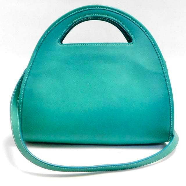 Front view of a turquoise Coach cow leather zip-dome handbag with a top cutout handle and a long shoulder strap.