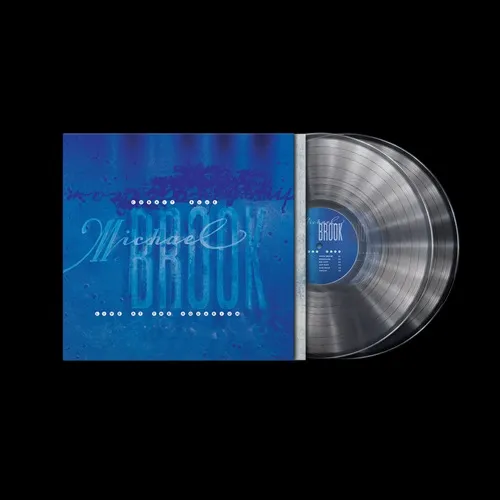 A crystal clear vinyl record partially pulled from a cobalt blue album sleeve on a black background.