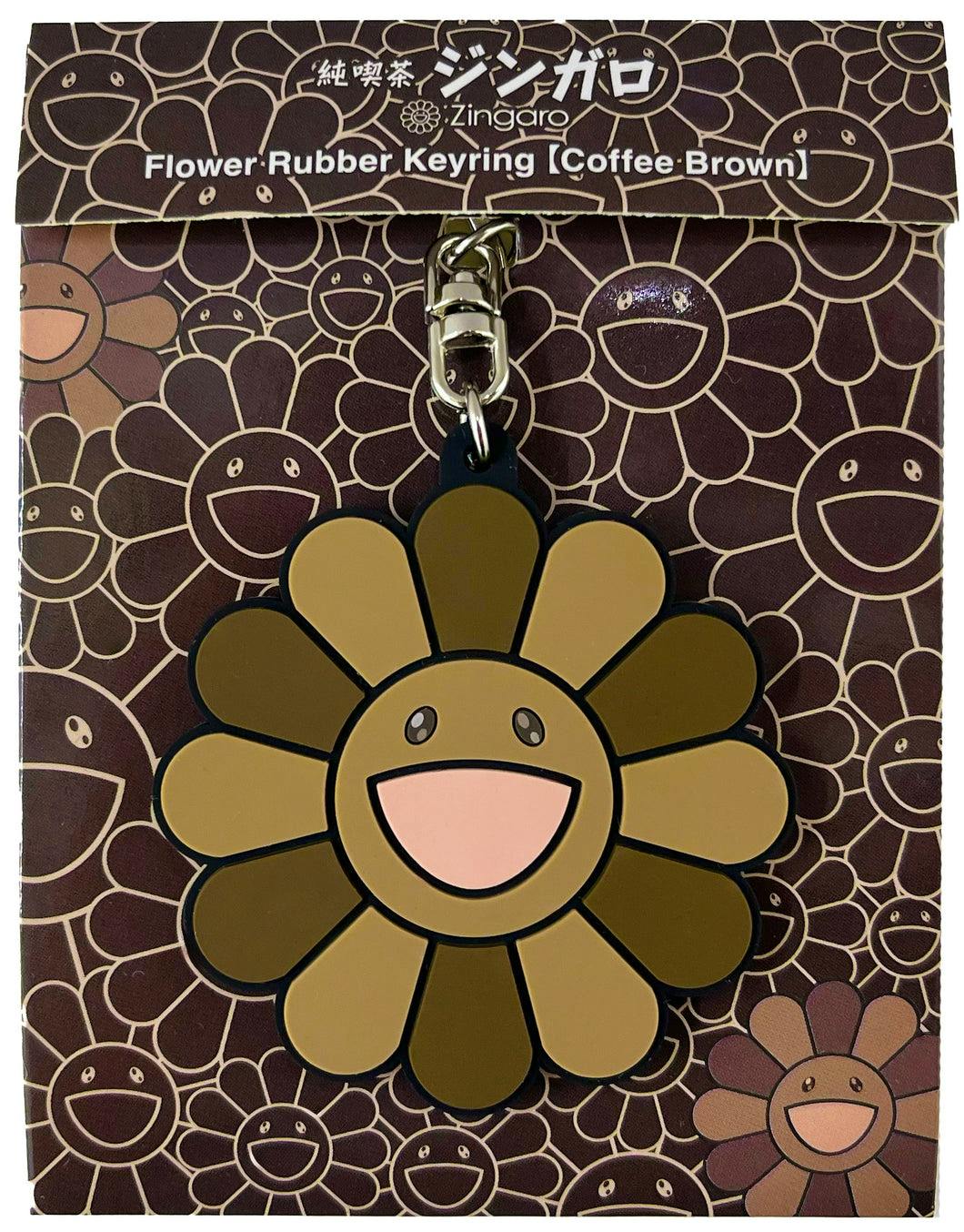 Coffee-brown flower-shaped rubber keyring with a smiling face shown on its printed backing card.