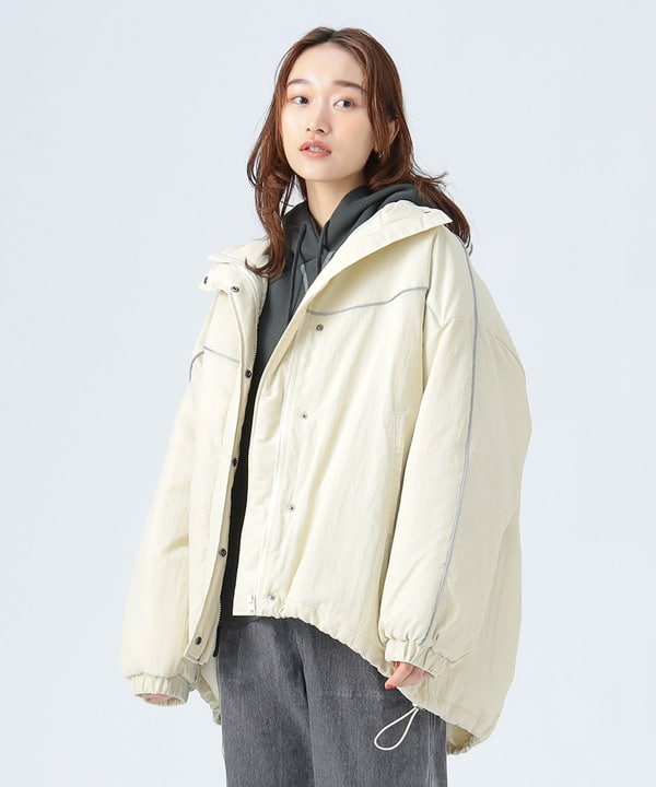 Woman modeling a light-colored women's nylon short coat with a hood, worn over a dark hoodie.