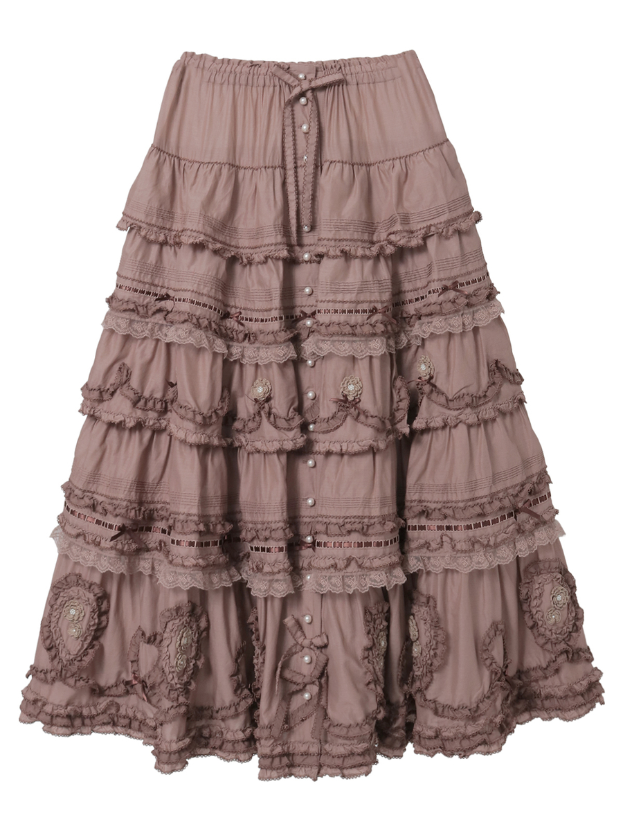 Front view of the women's tiered frill cotton skirt with rose motifs and pearl-button details in mauve on a white background.
