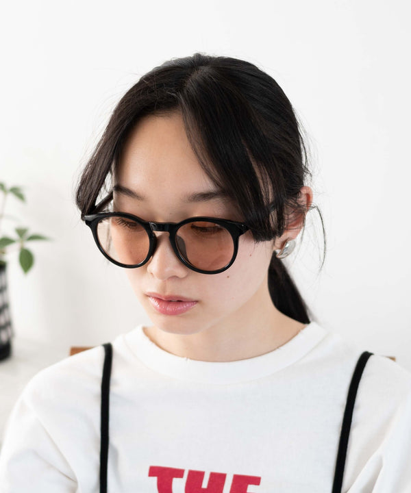 A person wearing black-framed sunglasses with brown-tinted lenses.