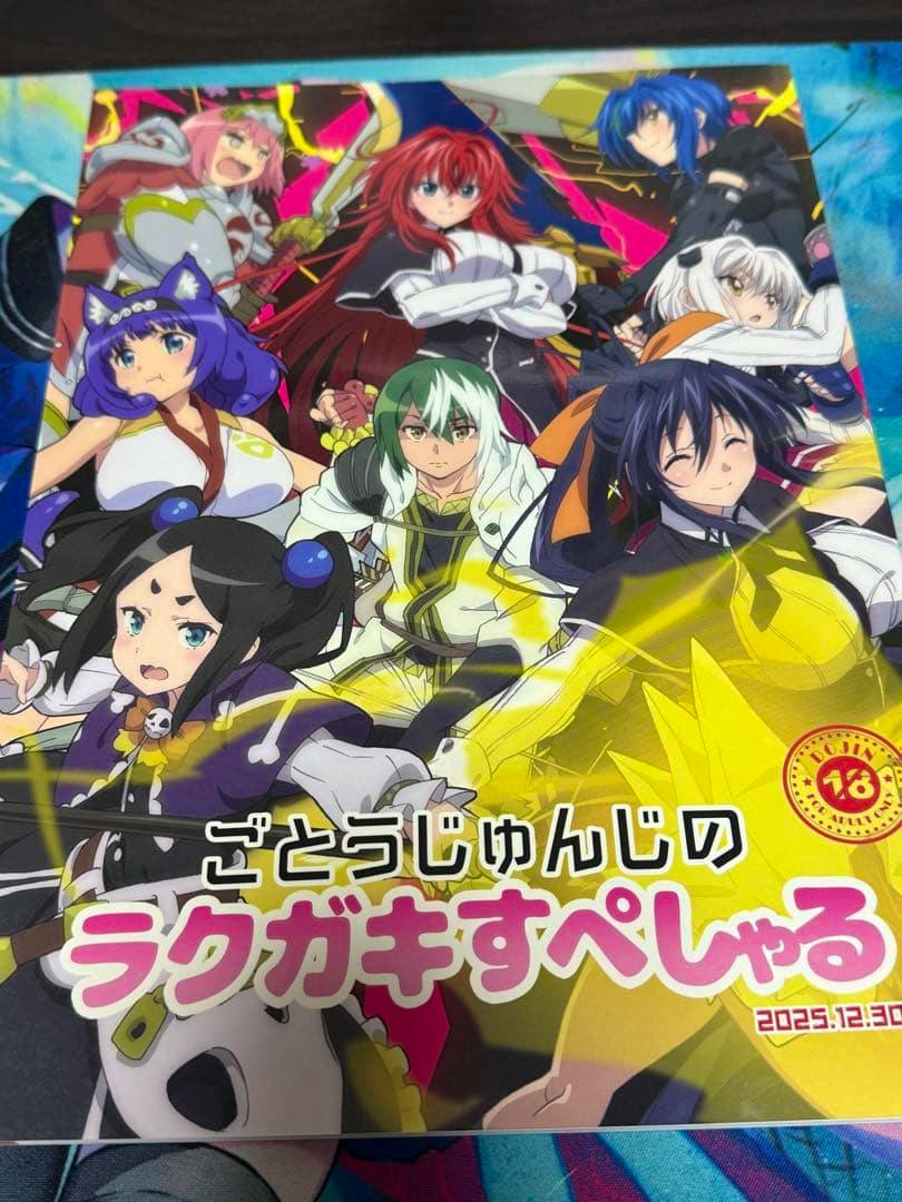 Photo of the illustration book's front cover showing multiple anime-style characters and Japanese title text.