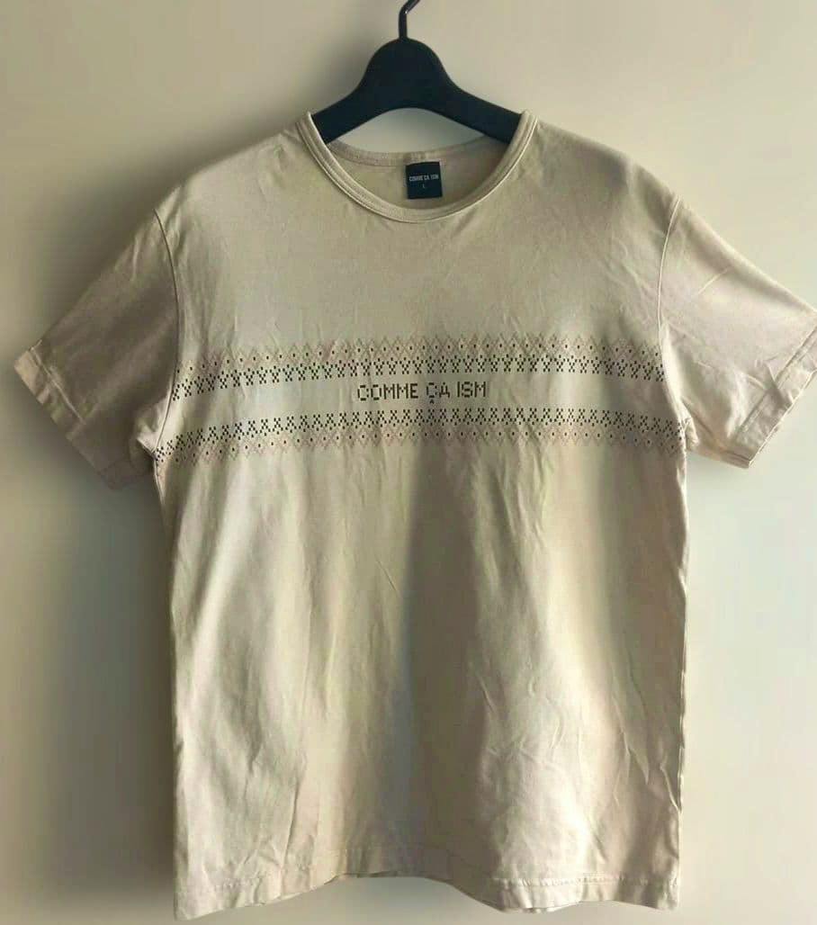 Ivory men's COMME CA ISM T-shirt (size L) hanging on a hanger showing the front with the logo embroidery across the chest.