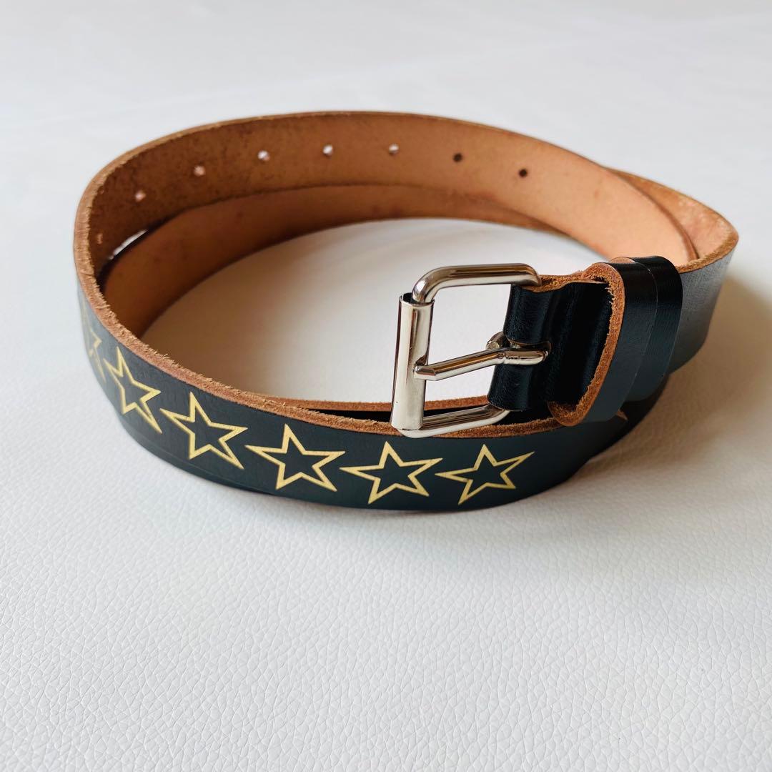 Black cow leather belt with gold star print and a silver buckle laid on a white surface.