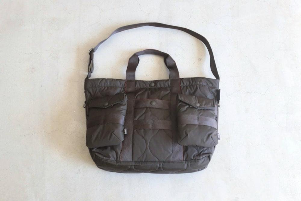 Front view of a quilted nylon 2WAY tote bag with top handles, an adjustable shoulder strap, and two front flap pockets on a light background.