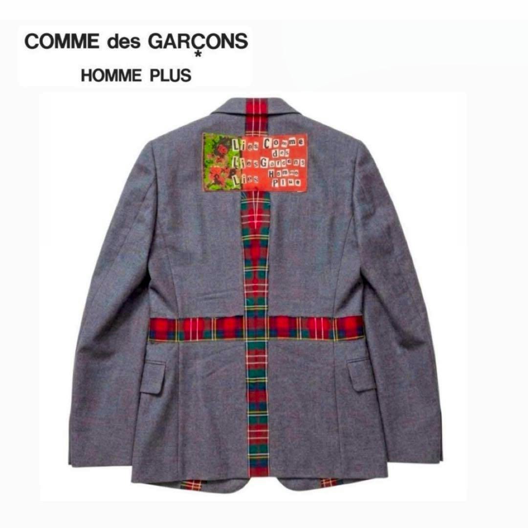 Back view of a grey Comme des Garçons Homme Plus men's jacket with red tartan cross detailing and a rectangular patch at the upper back.