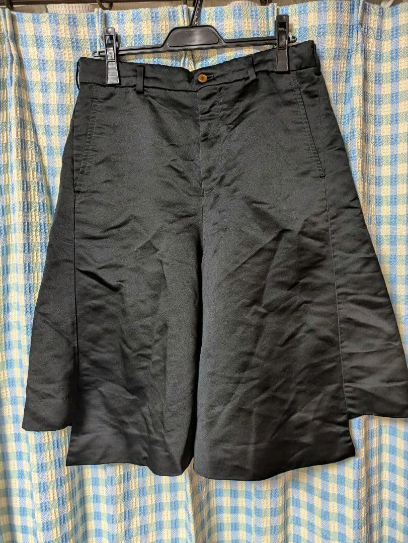 Front view of the black wide polyester men's shorts (size M) hanging on a hanger.