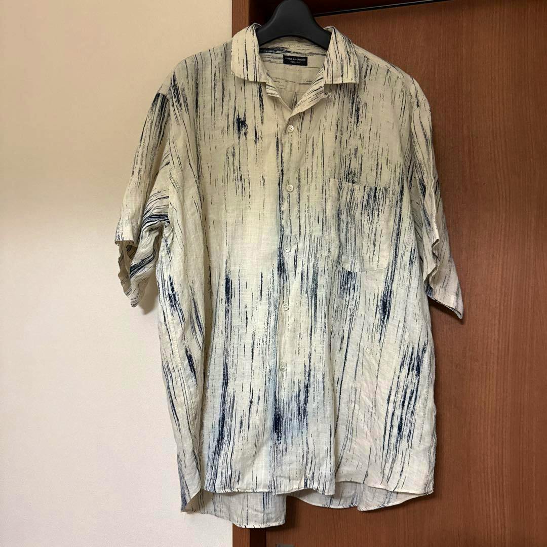 Front view of a linen button-up shirt with vertical blue brushstroke pattern hanging on a hanger.