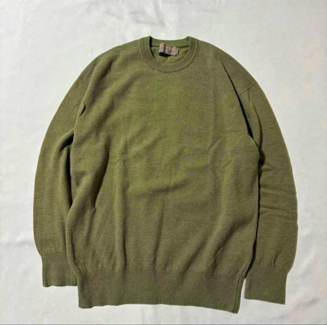 Front view of a green cotton knit sweater laid flat on a light background.