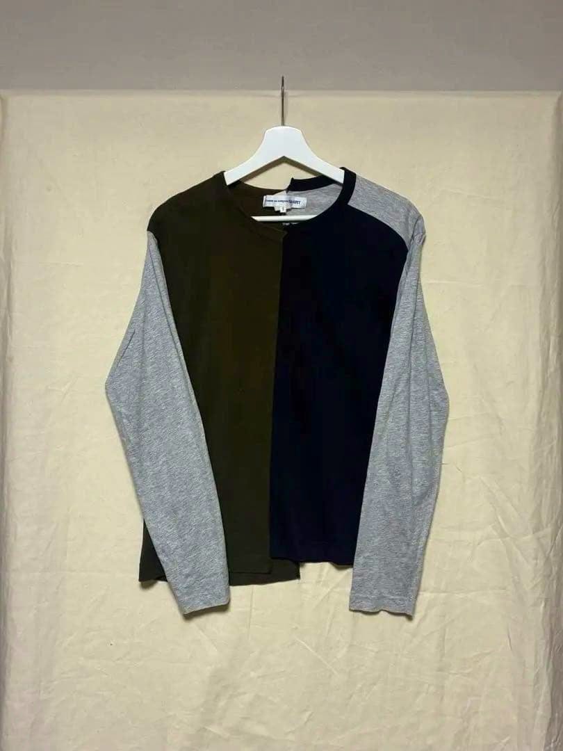 Front view of the COMME des GARÇONS long-sleeve cotton sweatshirt with contrasting center panels and grey sleeves hanging on a hanger.