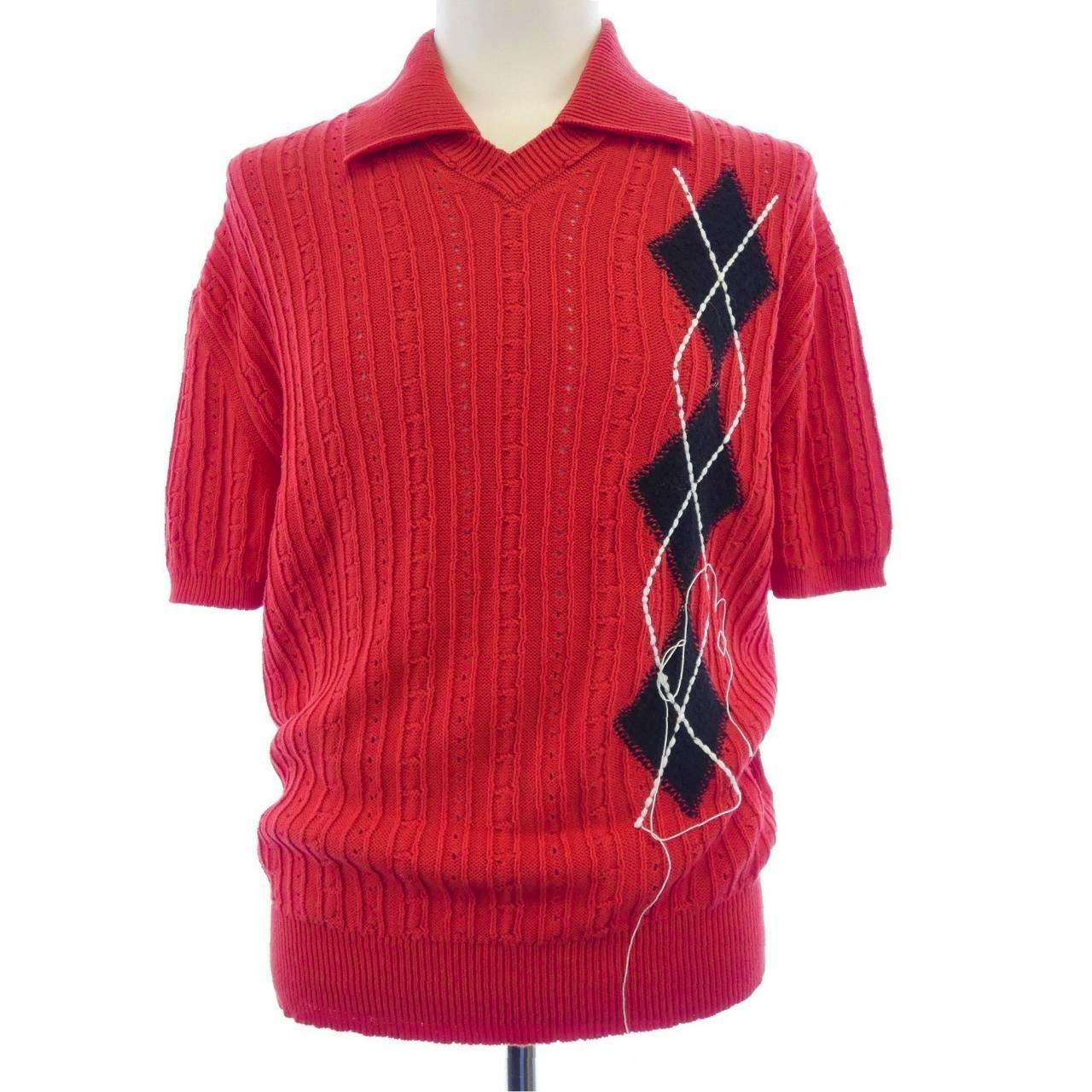 Red knit sweater with a collar, short sleeves, and a vertical black argyle design shown on a mannequin.