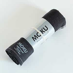 Rolled charcoal MOKU face towel with a paper label around it on a white background.