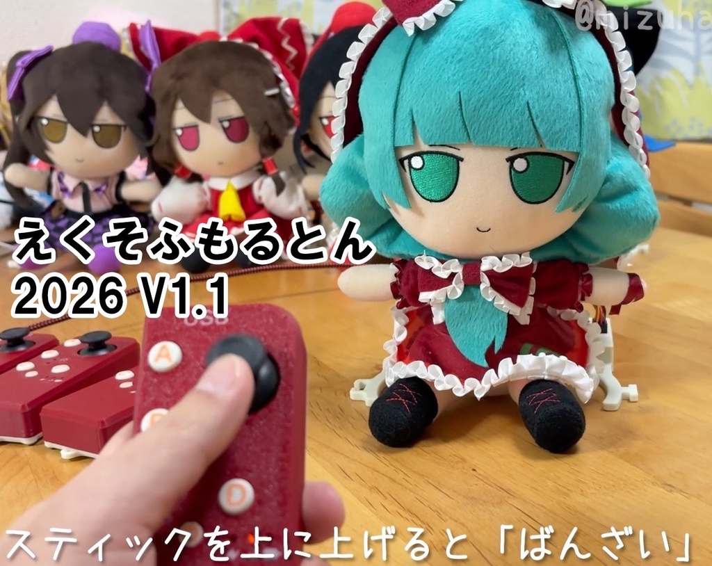 A hand holding a red video game controller with several plush dolls in the background.