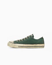 Side profile of an All Star low-top green canvas sneaker with an aged, dirty-looking sole.