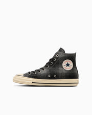 Side view of a black high-top All Star canvas sneaker with an aged beige sole and circular All Star logo on the ankle.