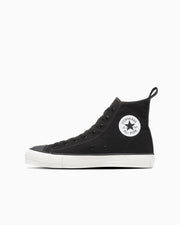 Side view of a black canvas high-top sneaker with a white sole and round star ankle patch on a white background.