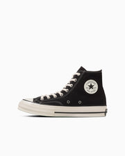 Side view of a black high-top canvas sneaker with white rubber toe cap, white sole, laces, and round ankle patch.