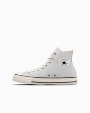 Side profile of a light gray high-top canvas sneaker showing the circular All Star ankle patch on a white background.