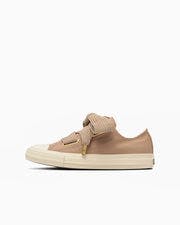 Side view of a beige canvas low-top sneaker with ribbon laces and an off-white sole.
