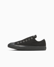 Side view of a black canvas slip-on sneaker with rubber sole and toe cap on a white background.