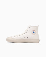 Side view of a white high-top canvas sneaker showing the rubber sole and circular All Star logo on the ankle.