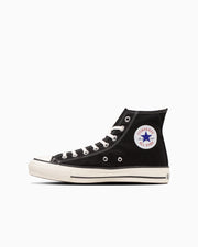 Side profile of a black canvas high-top sneaker with white rubber sole and circular ankle patch.