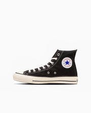 Side profile of a black high-top canvas sneaker with a white sole and a round All Star ankle patch.