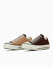 Pair of low-top canvas sneakers in tan and brown on a white background.