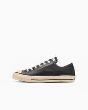 Side view of a black leather low-top sneaker on a white background.