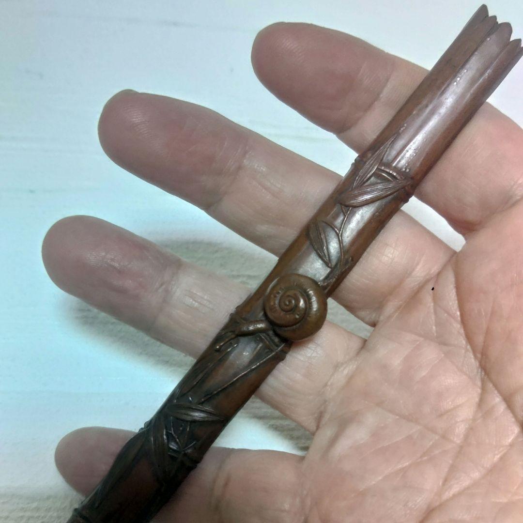 Hand holding a carved brown paperweight with a snail decoration visible.