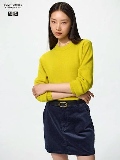 Female model wearing the corduroy mini skirt shown from the front with a yellow sweater.